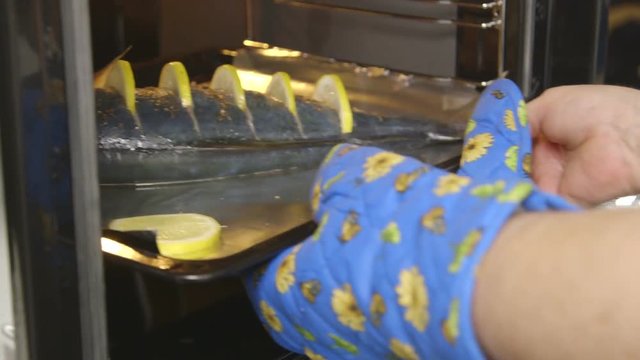 Cooking whole roasted fish seriola with lemon baked in the oven. Chef puts a baking sheet with raw amberjack takes out cooked fish from the oven. Edited sequence.