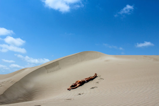 Beautiful woman lying on the sand alone at desert.