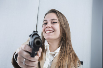 Bella e sorridente segretaria bionda punta una  pistola scherzando
