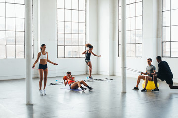 Young multiethnic teamwork doing exercises at indoors bootcamp.