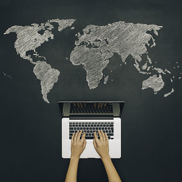 Hands typing on laptop with world map