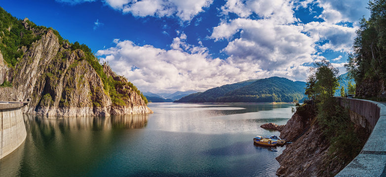 Panorama of a mountain lake Near the dam. Beautiful blue sky with clouds