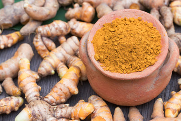 Turmeric powder in clay pot , turmeric capsules and fresh turmeric root on wooden background