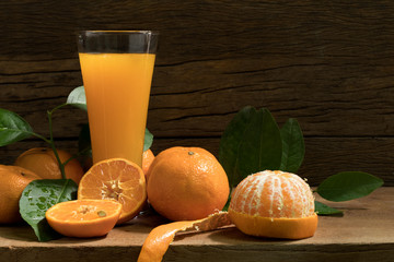Orange juice and orange peel off on wooden table in dim light night.Still life style and selective...