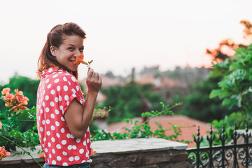 Young woman smelling flower in the garden enjoying sunset