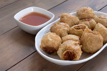 Deep fried crap meat roll on white dish on wooden table.Thai food and selective focus.