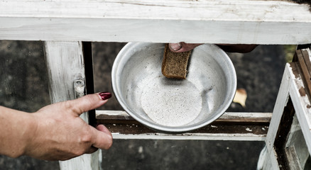 In his hand clamped aluminum plate and a piece of bread. The plate and the bread are passed through the window.
