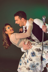 Happy handsome couple singing and having fun holding retro microphone