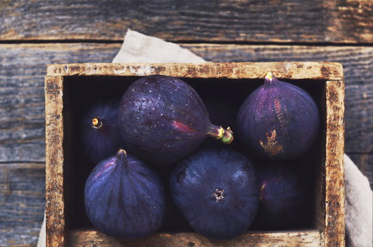 Purple figs in wooden crate with copy space on rustic wooden background
