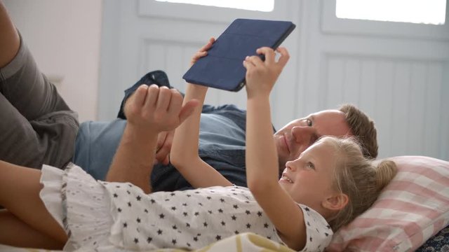 Father And Daughter Lying On Floor Using Digital Tablet