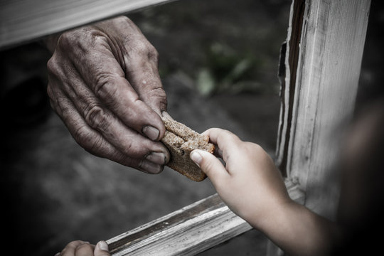 In his hand clutching a piece of bread. The bread passed through the window.
