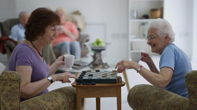 Cheerful senior ladies playing draughts in a nursing home.