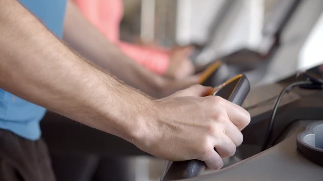 Man pressing buttons on a running machine at gym, detail
