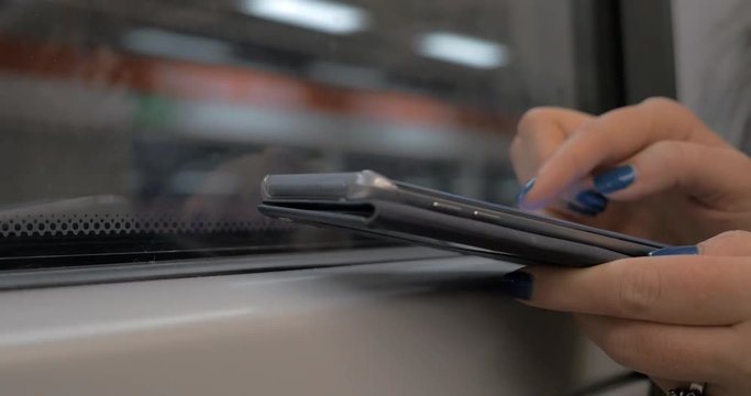 Close-up shot of female hands using smart phone to play game or browse web during everyday subway travel
