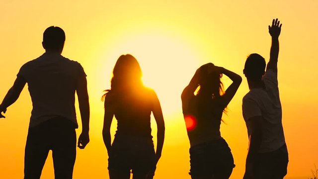 The silhouettes of dancing people on the background of the sunrise. slow motion