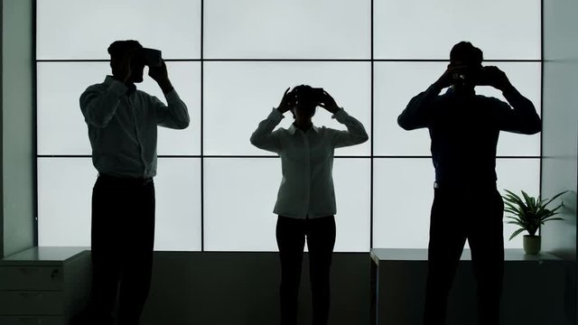 Business team in silhouette trying out virtual reality viewers on white background