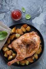 Top view of oven baked halved chicken served with potato wedges, vertical shot