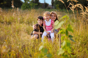 Naklejka na ściany i meble A woman and her children are sitting in high grass
