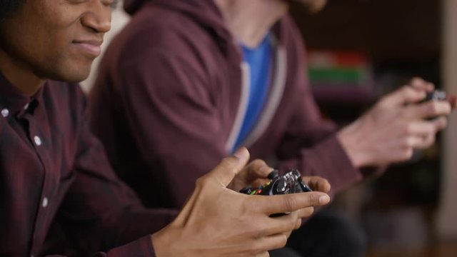 Competitive male friends playing video games at home.