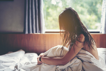 woman sit on a bed in a bedroom - concept photo of Sexual assault.,Woman violence concept.