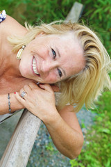 femme senior blonde souriante dans parc nature