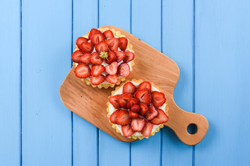 Healthy dessert. Strawberry tartlets with mascarpone on wooden boards on bright blue background