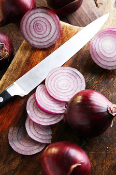 Red onions circles and red onions on board against wooden backgr
