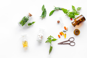 Herbal medicine. Leaves, bottles, pills and sciccors on white background top view