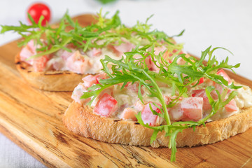 bruschetta with tomatoes and fresh spinach on a light wooden background