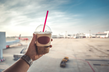 Hand Holding Ice Coffee in Air Port - Holiday Travel Concept