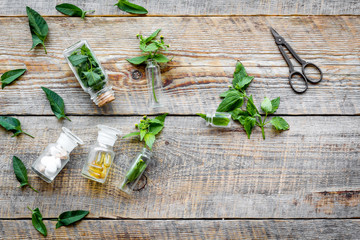 Medicinal herb in bottles on wooden background top view copyspace