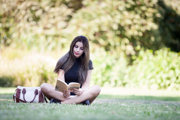 Beautiful young woman reading a book in the pak. Person enjoying reading outdoor