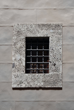 concrete window with thick security metal bars in a grey stone wall