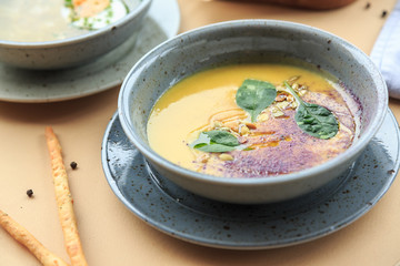 Pumpkin and carrot soup with cream and parsley on dark wooden background Top view