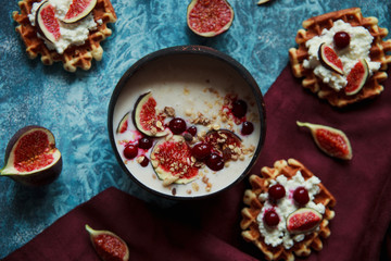 Overhead still life of smoothie bowl, belgian biscuit waffles with cottage cheese, fresh figs and cherry. Healthy vegetarian breakfast.
