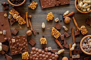 Preparing chocolate. Chocolate bars, nuts, cinnamon on dark wooden background top view