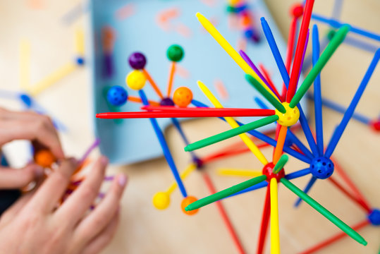 Two little girls playing with lots of colorful plastic sticks kit indoors. kids having fun with building  geometric figures and learning mathematics in preschool or primary class of school