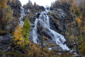 Obraz premium yellow larch and waterfalls in the autumnal Alps