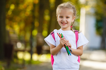 little schoolgirl with a backpack and pencils