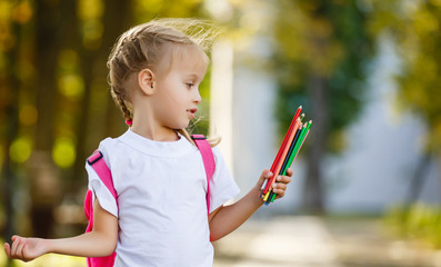 little schoolgirl with a backpack and pencils