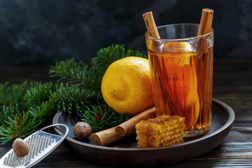 Hot tea with spices and lemon on a wooden tray.