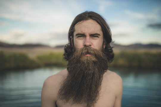 A handsome bearded man with his dogs in beautiful desert hot springs during the golden hour
