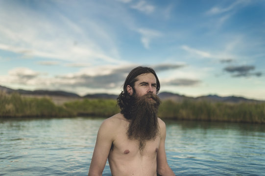A handsome bearded man with his dogs in beautiful desert hot springs during the golden hour