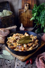 Stewed cabbage with pork in a cast-iron frying pan. Rustic style.