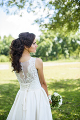 Beautiful bride outdoors on the meadow on a wedding day. Joyful moment of happiness