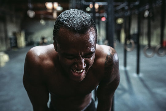 Young, fit black man recovering after training hard in fitness gym