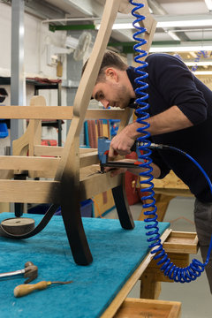 Craftsman attaching webbing to a chair as part of the renovation process.