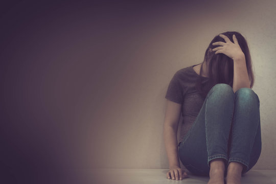 sadness young woman sitting on wood floor looking at empty dark area feeling unhappy and afraid on white wall background with battered abused woman concept.