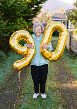 elderly woman holding number balloons for ninetieth birthday