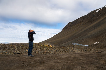 Fototapeta na wymiar Man using binoculars in the mountains at Svalbard